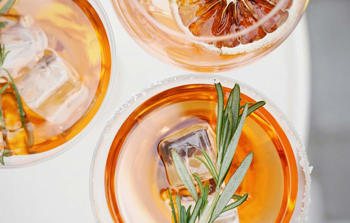 overhead view of cocktail glasses with orange liquid garnished with rosemary