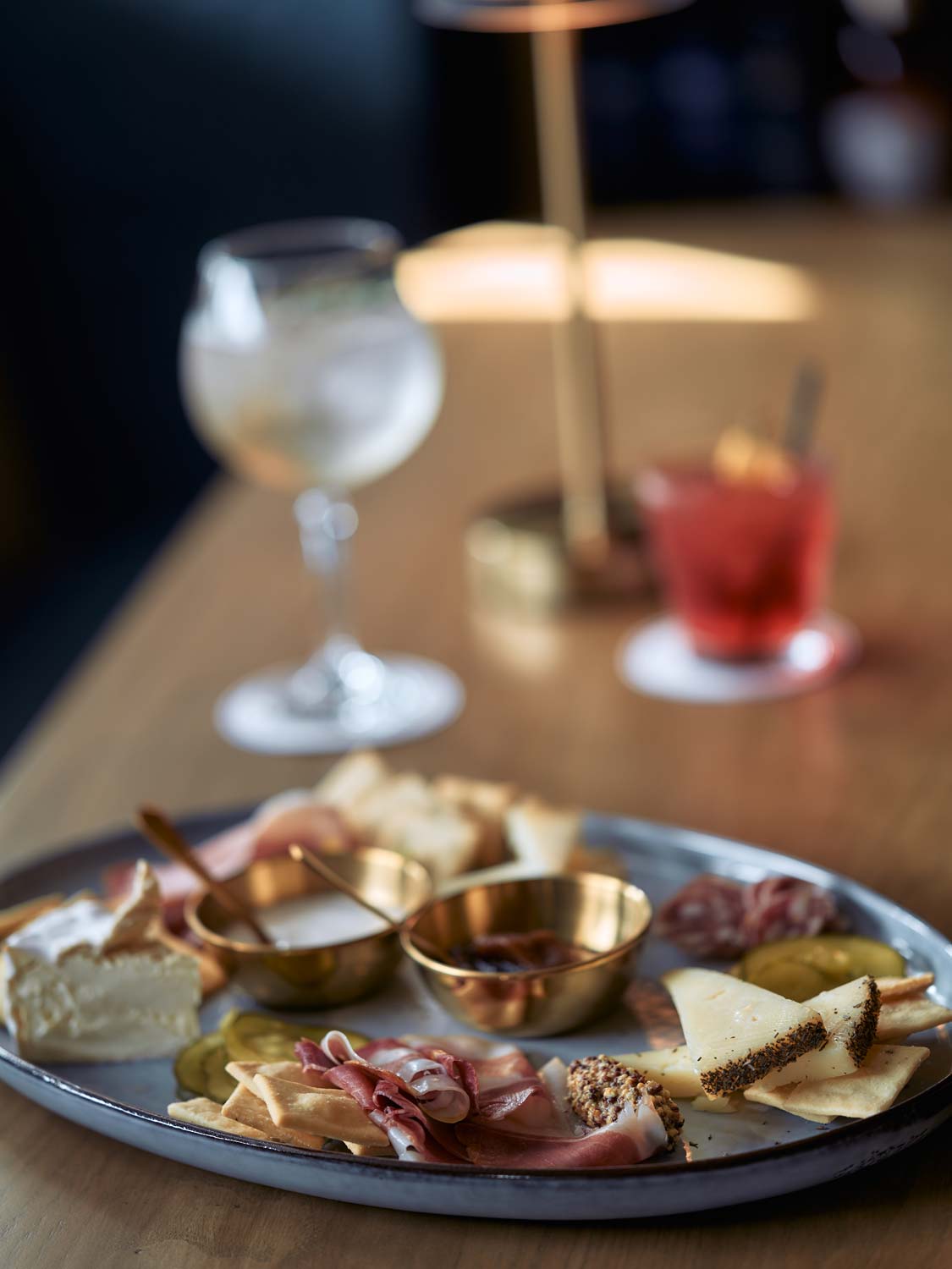 a crisp cocktail is a clear cocktail in a lowball glass garnished with orange, against a concrete background